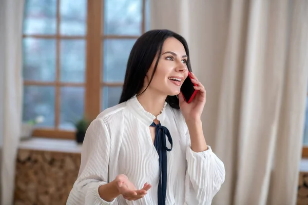 Молода жінка розмовляє по телефону, щасливо посміхаючись — стокове фото