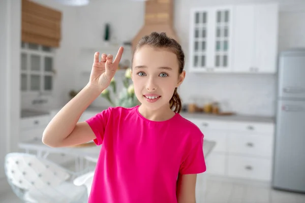 Linda chica con una camiseta brillante levantando el dedo — Foto de Stock