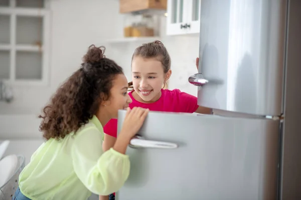 Dos chicas abriendo la nevera sintiéndose emocionadas — Foto de Stock