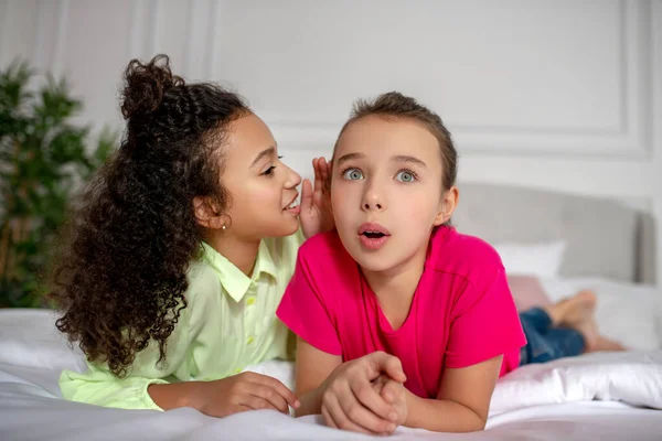 Meisje in helder tshirt luisteren naar haar vriend en kijken verbaasd — Stockfoto