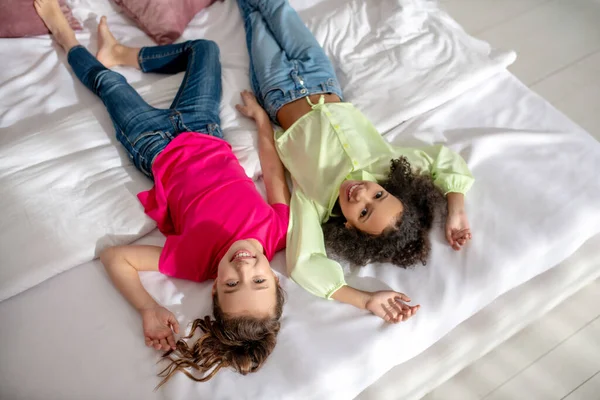Dwie piękne dziewczyny leżące na łóżku i wyglądające jak marzenie — Zdjęcie stockowe