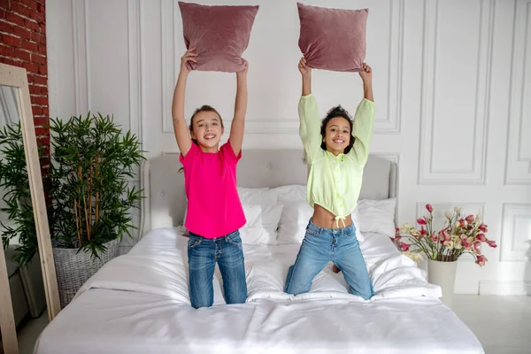 Dua gadis cantik memegang bantal dan tampak menikmati — Stok Foto