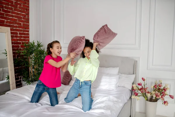 Dua gadis cantik berkelahi dengan bantal di kamar tidur — Stok Foto