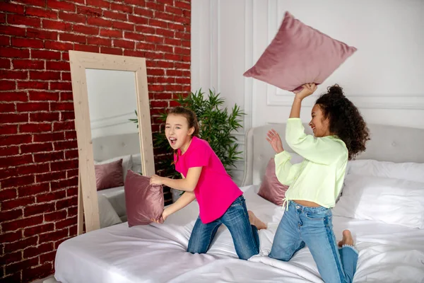 Dua gadis cantik bermain-main dengan bantal di kamar tidur — Stok Foto
