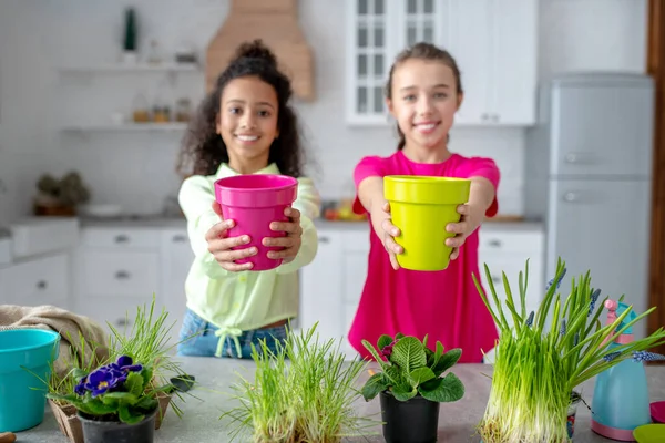 Zwei süße Teenager zeigen Töpfe mit Blumen — Stockfoto