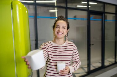 Buzdolabının yanında duran genç bir kadın, Asya yemek kutusunu tutuyor.