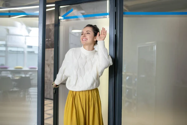 Young woman entering the room, waving happily