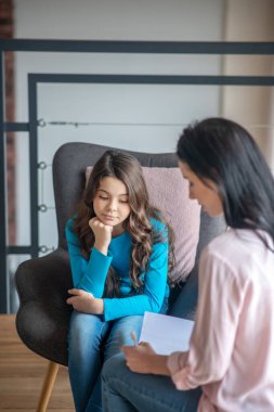 Uzun saçlı, mavi gömlekli, üzgün bir genç.