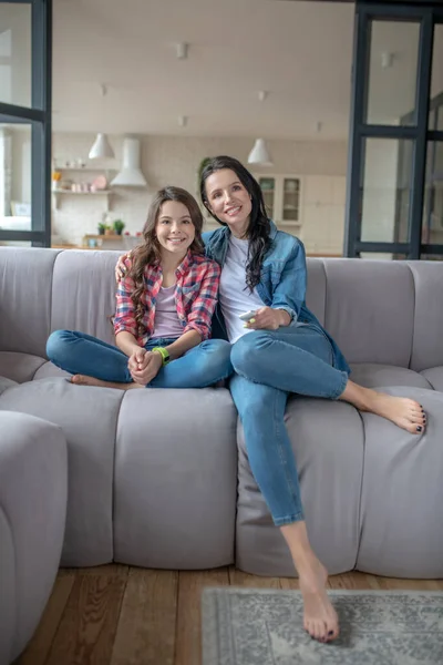 Mãe e sua filha sentados ao lado um do outro e olhando satisfeito — Fotografia de Stock