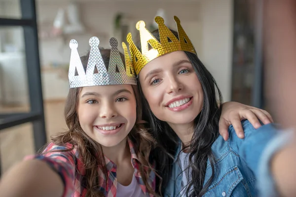 Mamá e hija llevando coronas y sonriendo —  Fotos de Stock