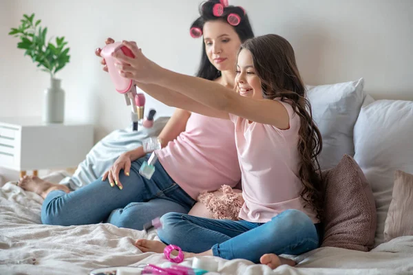 Menina de cabelos escuros em uma camiseta rosa sentindo-se bem brincando com cosméticos — Fotografia de Stock