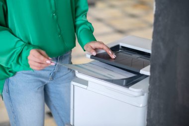 Fotokopi makinesinin yanında kağıt tutan kadın eller..