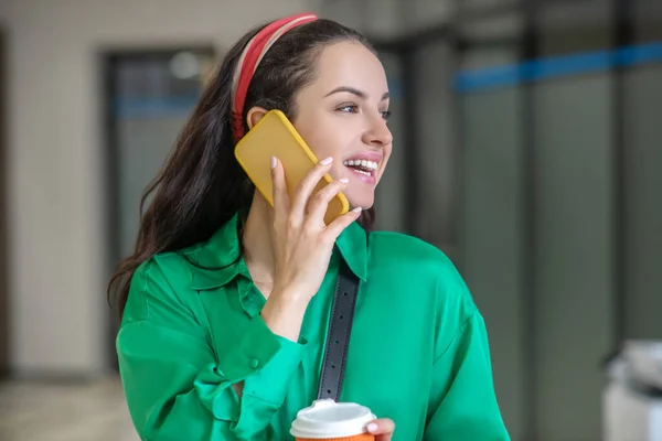 Mujer morena con café hablando en un smartphone . — Foto de Stock