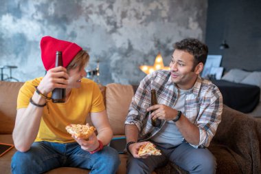 Kanepede oturup bira içen iki genç adam.