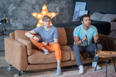 İki arkadaş bira içiyor ve heyecanlı görünüyorlar.