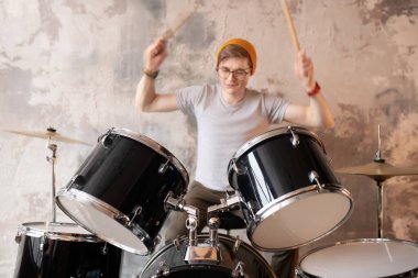 Young man in a red hat playing the drums clipart