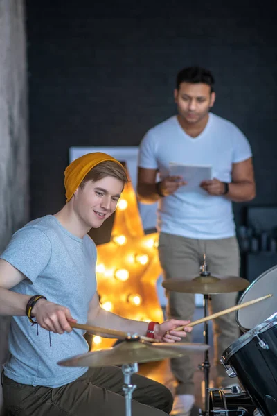 Joven con una sensación de sombrero naranja disfrutando tocando la batería — Foto de Stock