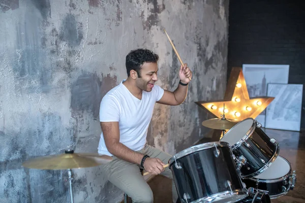 Tmavovlasý mladý latino v bílém tričku hrající na bubny — Stock fotografie