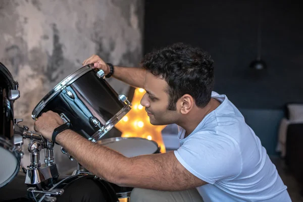 Donkerharige jongeman in een wit tshirt druk bezig met de drums — Stockfoto