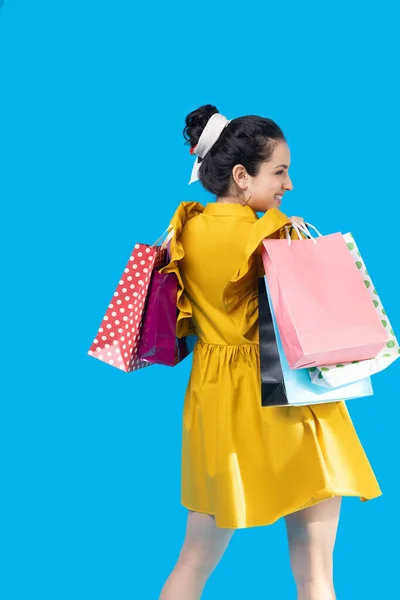 Mujer joven en un vestido de mostaza sosteniendo bolsas de compras y sintiéndose bien — Foto de Stock