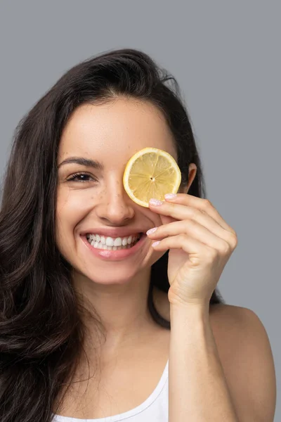 Leende mörkhårig flicka med orange i handen — Stockfoto