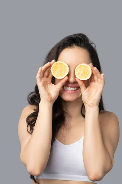 Chica de pelo oscuro cerrando los ojos con naranja y sonriendo — Foto de Stock