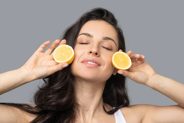 Hermosa chica morena sosteniendo mitades naranjas en sus manos — Foto de Stock