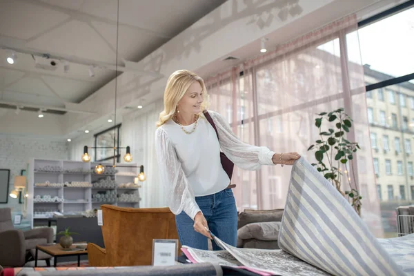 Mujer en blusa y jeans mirando muestras de alfombras . — Foto de Stock