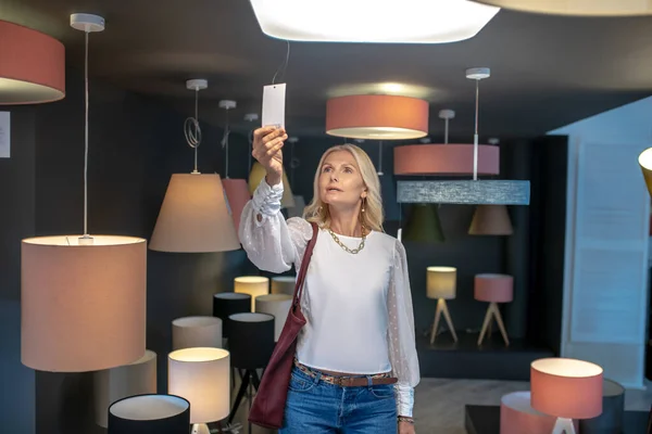 La mujer está en el departamento de iluminación en una tienda de muebles . — Foto de Stock