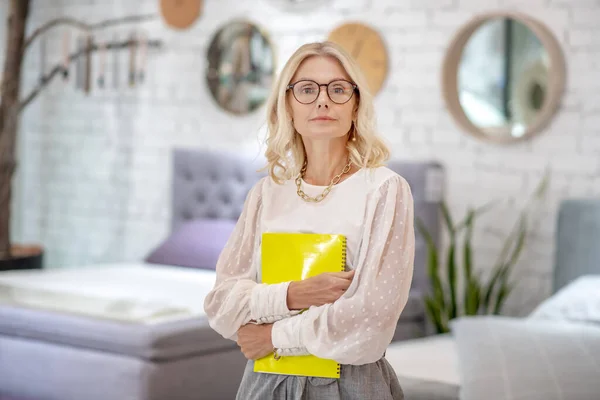 Mujer de negocios seria agarrando un cuaderno amarillo para notas . — Foto de Stock