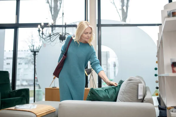 Mujer cerca del sofá mirando una almohada verde . — Foto de Stock