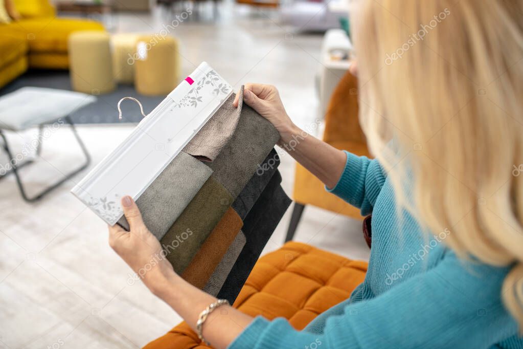 Fabric samples for upholstered furniture in female hands.