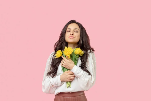 Jovem mulher de cabelos escuros segurando flores amarelas e se sentindo satisfeito — Fotografia de Stock