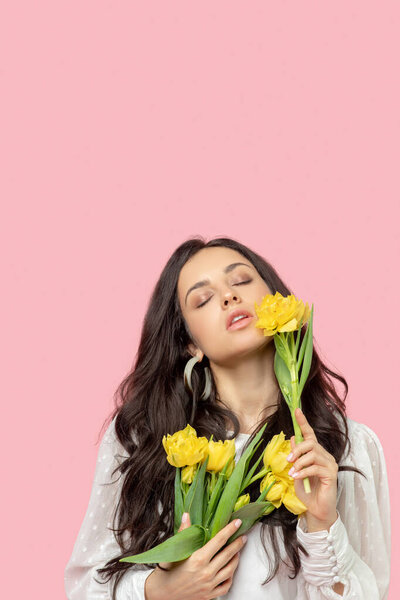 Молодая довольно темноволосая женщина с желтыми цветами и расслабленным видом

