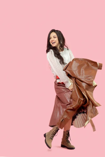 Young pretty dark-haired woman in a pleated skirt holding a leather jacket — Stock Photo, Image