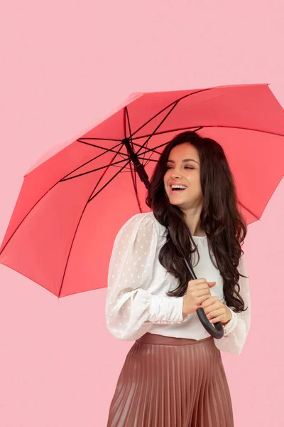Молода красива темноволоса жінка в плісированій спідниці тримає червону парасольку і відчуває себе чудово — стокове фото