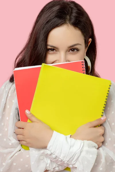 Jovem mulher em uma blusa branca segurando cadernos e sorrindo — Fotografia de Stock