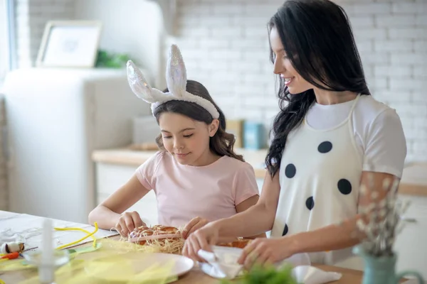 Lief meisje dragen Pasen bunnys oren bezig in de keuken met haar moeder — Stockfoto