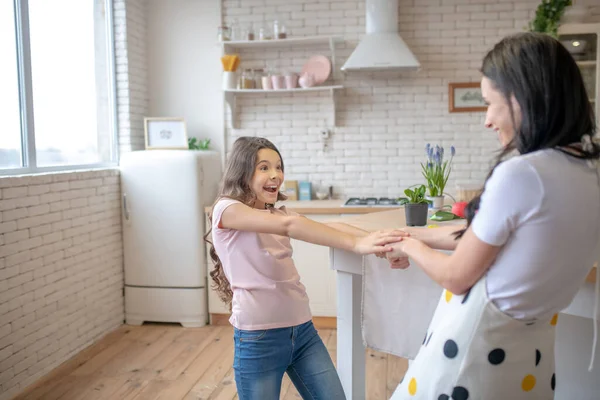 Barna nő és az ő aranyos lánya fogja egymás kezét és mosolyog — Stock Fotó