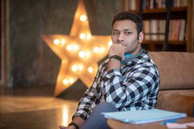 Kareli gömlekli yakışıklı adam ciddi görünüyor.