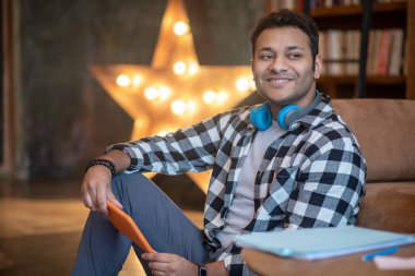 Kareli gömlekli yakışıklı adam güzelce gülümsüyor.