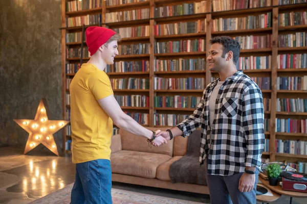 Due giovani uomini belli che si stringono la mano in piedi nella stanza — Foto Stock