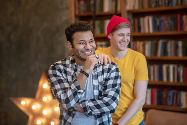 Dois jovens homens bonitos sorrindo alegremente de pé na sala — Fotografia de Stock