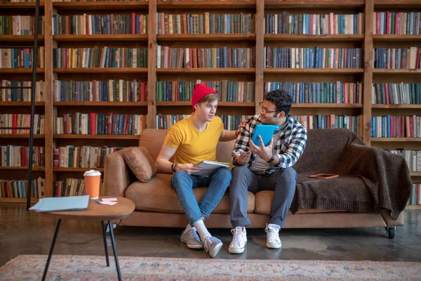 Two young men sitting on the sofa and talking — Stock Photo, Image