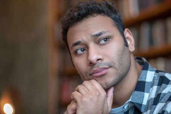 Hombre de pelo oscuro con una camisa a cuadros que se ve serio — Foto de Stock