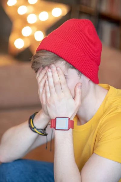 Joven con un sombrero rojo sentado con la cara cerrada — Foto de Stock