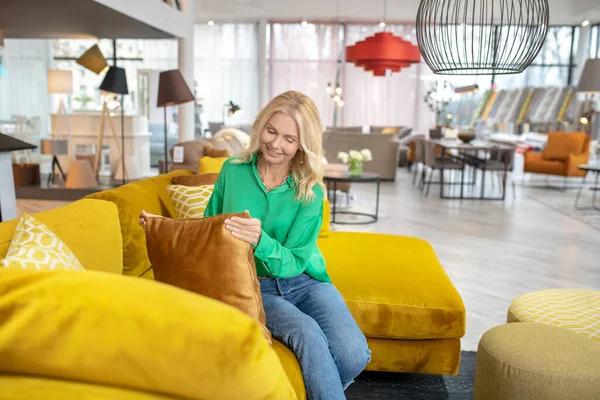 Blond kvinna i en grön blus som håller kudden — Stockfoto