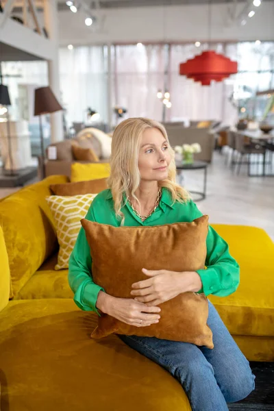 Блондинка красивая женщина в зеленой блузке сидит с подушкой — стоковое фото