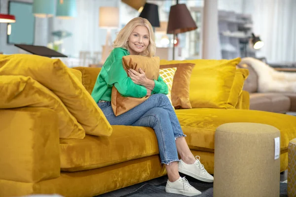 Mujer rubia en una blusa verde con aspecto soñador y positivo — Foto de Stock