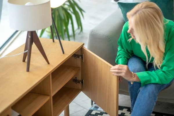 Mujer rubia en una blusa verde abriendo el cajón — Foto de Stock